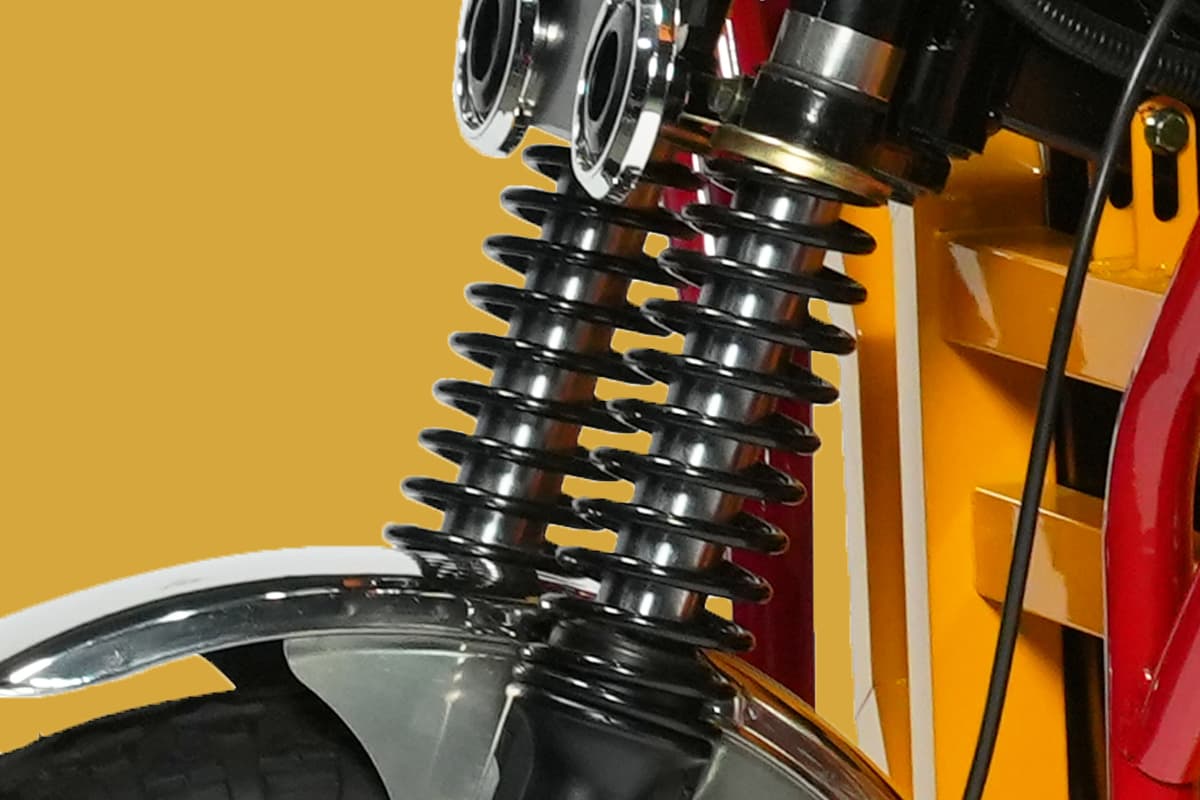 Close-up of a motorcycle suspension system with a yellow background