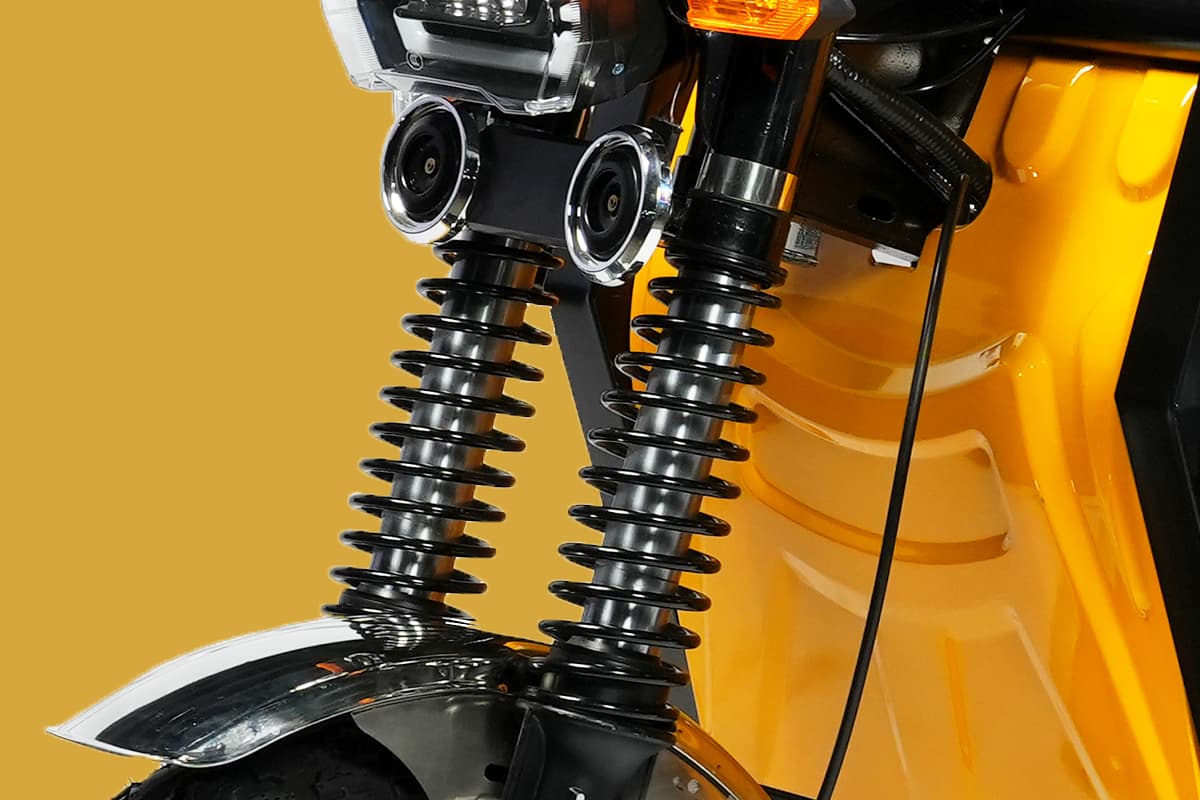 Close-up of a motorcycle suspension system with a yellow background