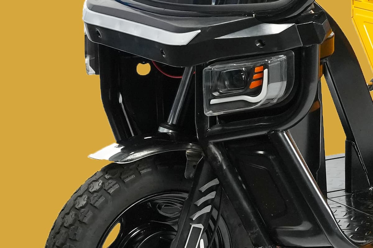 Close-up of a motorcycle's headlight and front wheel on a yellow background