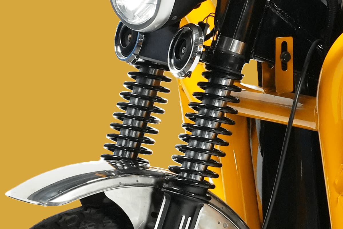 Close-up of a motorcycle's suspension system with a yellow background